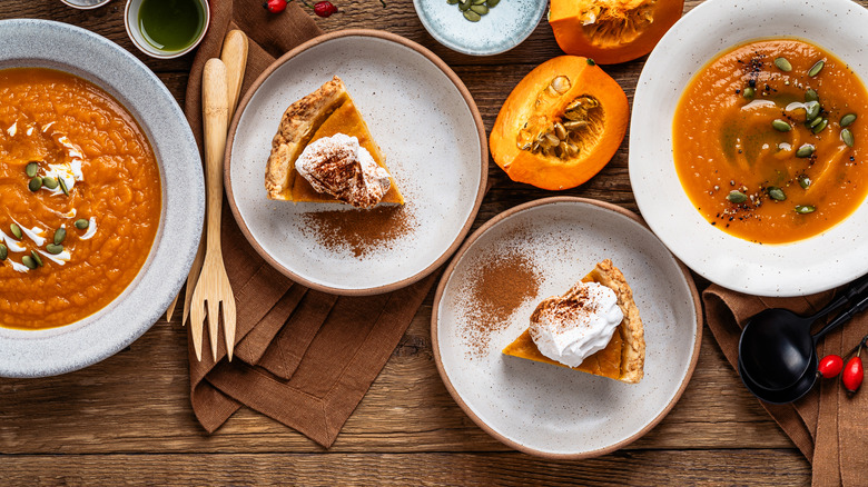 A thanksgiving table with pumpkin pie, raw pumpkins and pumpkin soup.