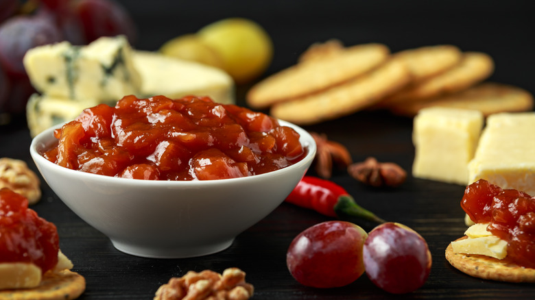 A bowl of chutney with cheese and crackers