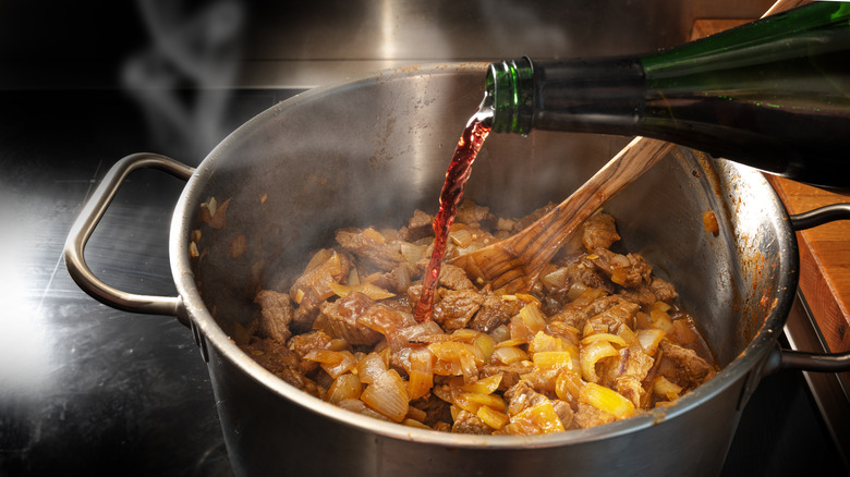 Wine being poured into meaty stew