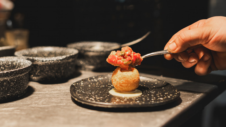 A hand scoops food onto a plate in a restaurant.