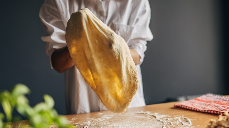 A cook stretches pizza dough