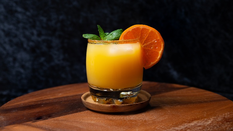 Orange whiskey sour with citrus wedge