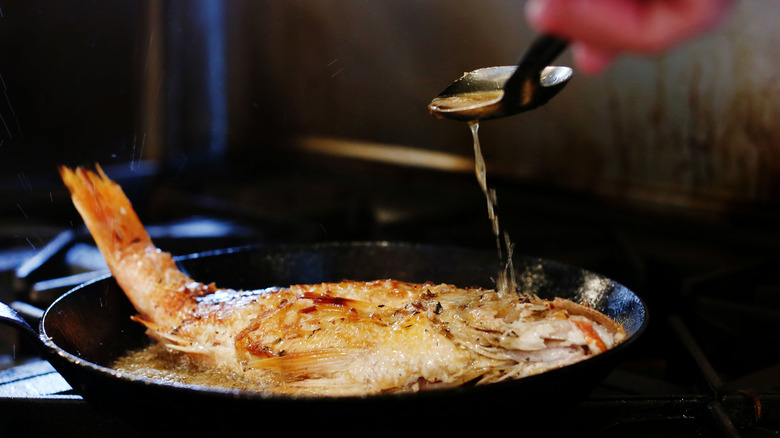 Pan with a whole fish being fried