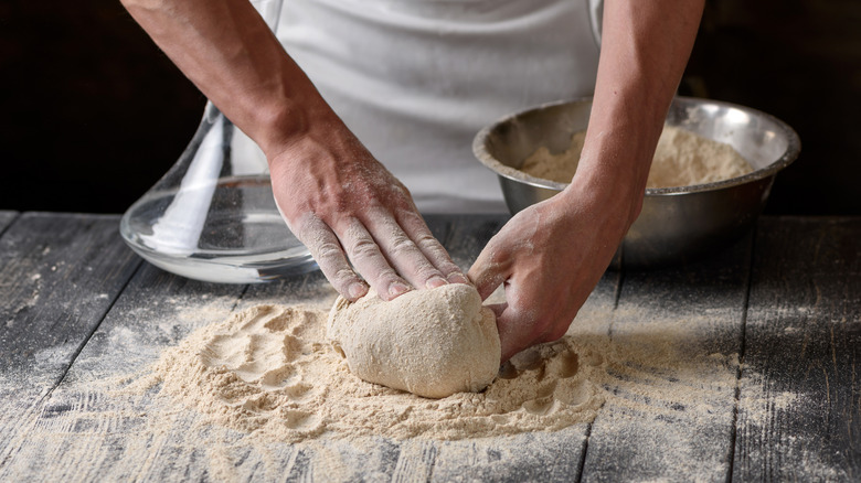 A chef kneads whole wheat flour into dough.