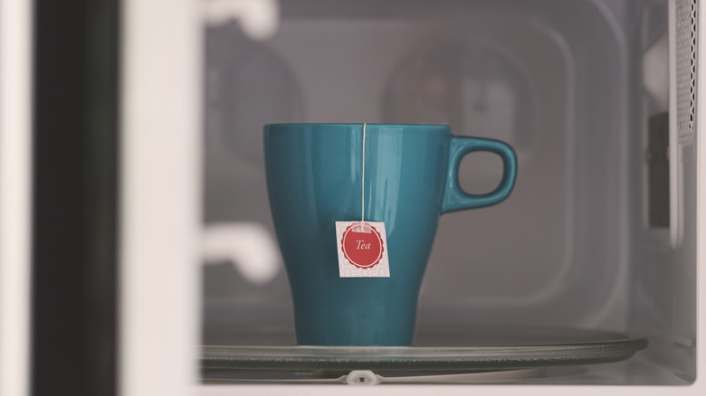 A cup with a tea bag in the microwave