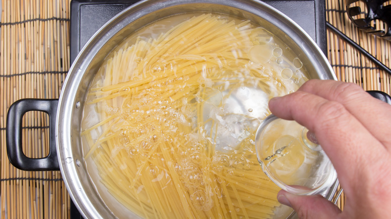 Adding oil to boiling spaghetti 