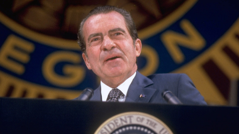 Former president Richard Nixon stands at a pulpit that bears the POTUS seal