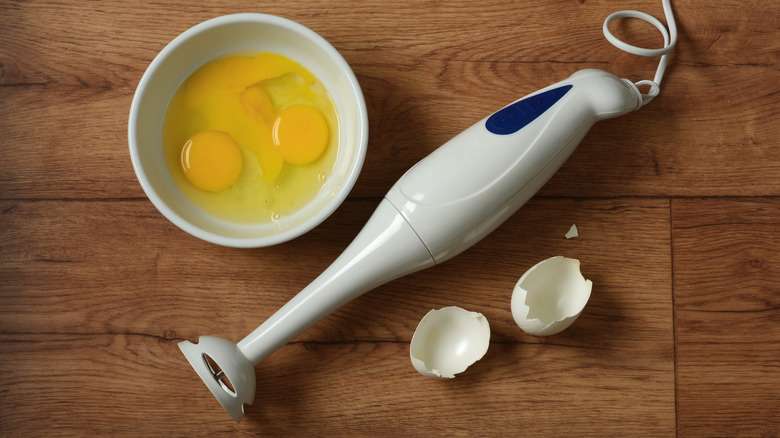 Eggs in bowl next to immersion blender