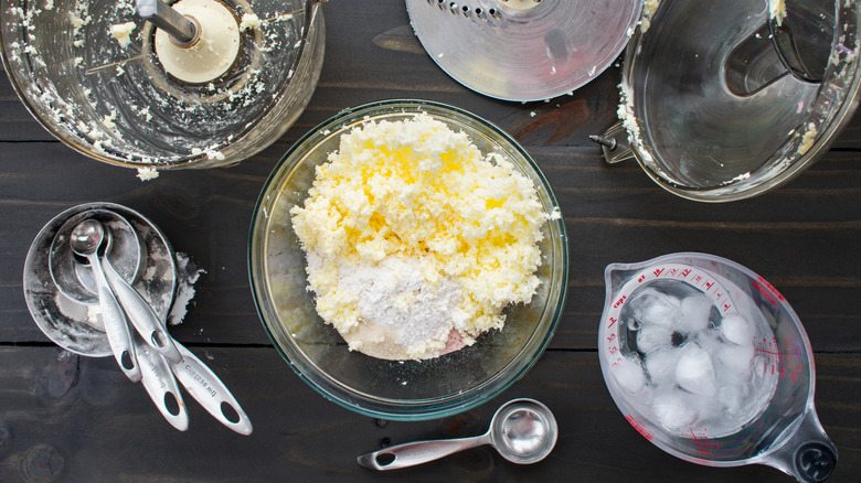 Bowls of pulsed butter and flour next to used measuring spoons