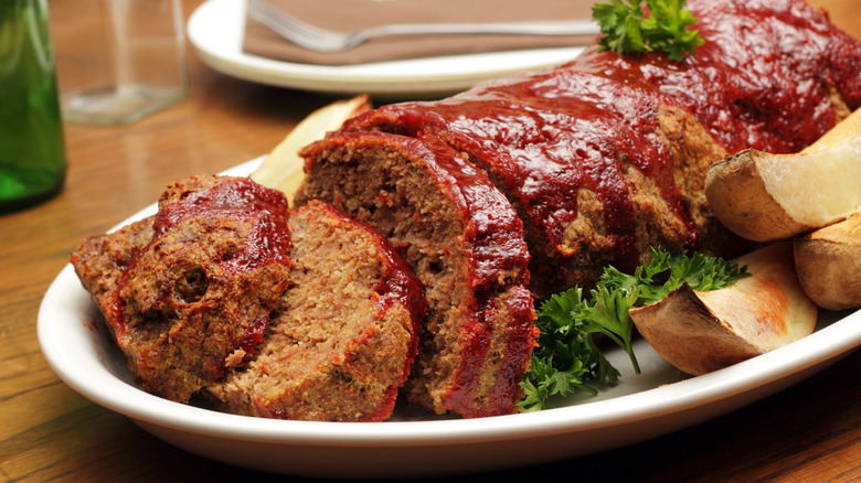 Meatloaf sliced on plate with potato wedges