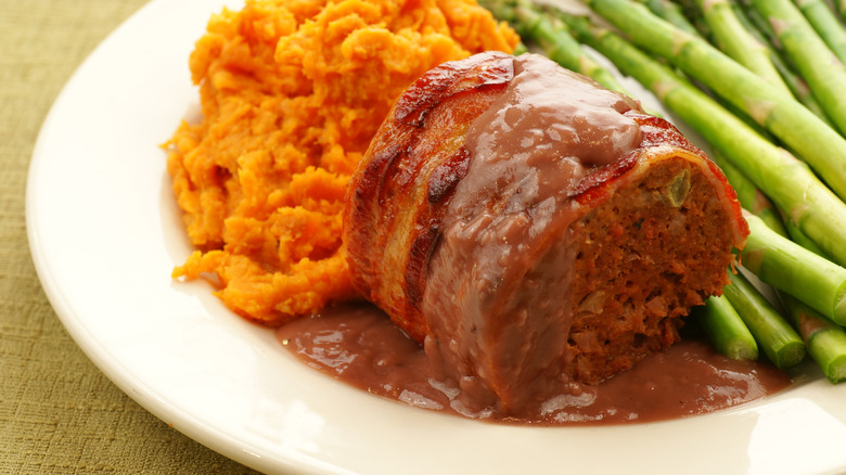 Bacon-wrapped meatloaf with red wine gravy and vegetables