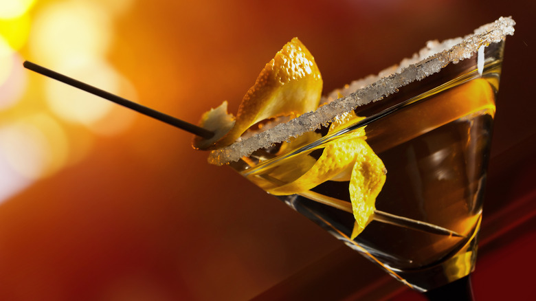 Yellow cocktail in martini glass with citrus peel spiral and cinnamon-sugar rim