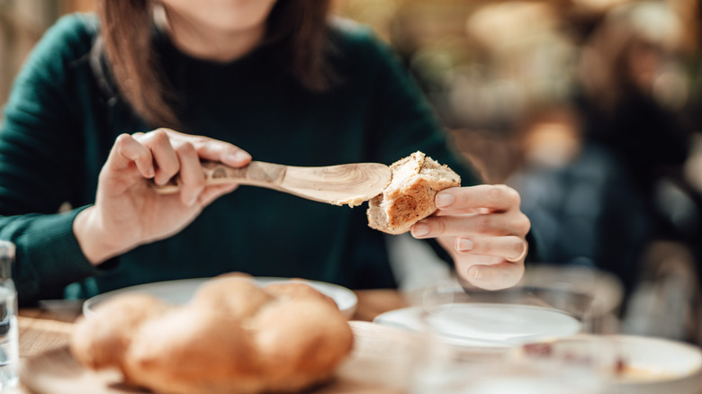 A woman spreading butter on bread with a spoon