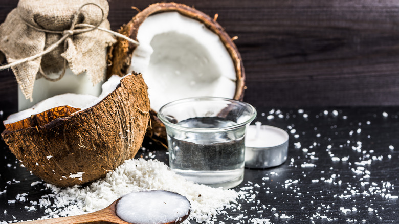 A cracked cocnut surrounded by shredded coconut, coconut water, and coconut milk