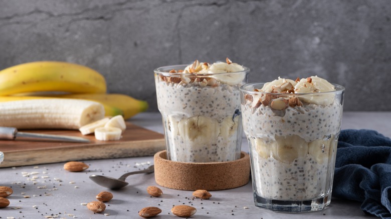 Glasses of overnight oats with seeds, bananas, and almonds