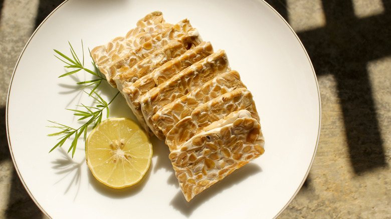 Sliced tempeh on plate with lemon wheel