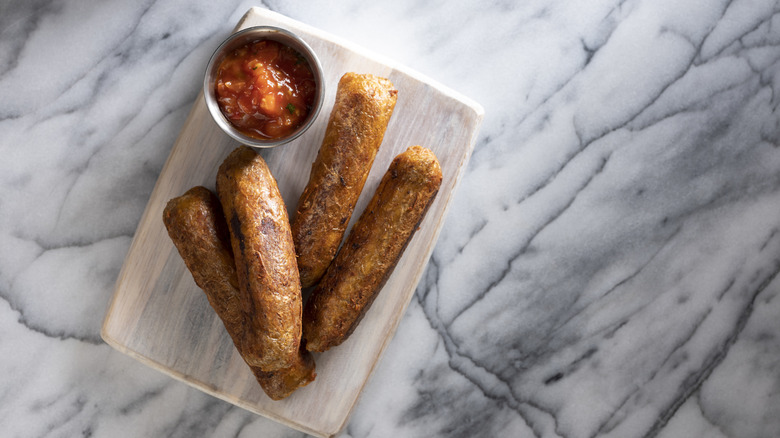 Plant-based sausages with ramekin of salsa