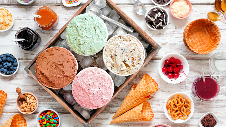 Four ice cream pints surrounded by different toppings