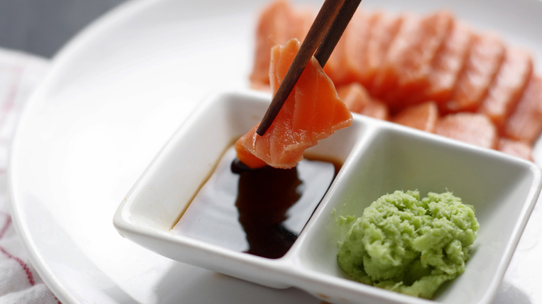 Dipping raw salmon into soy sauce