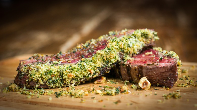 Sliced cooked steak on board with herbed crust