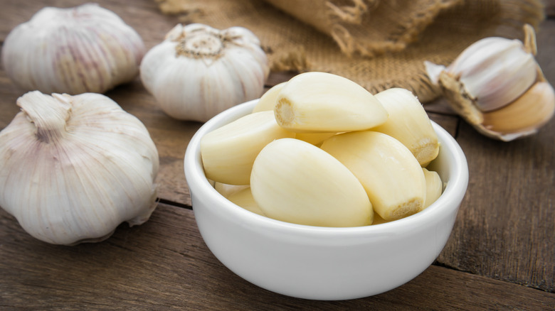 Peeled garlic in bowl with whole heads of garlic