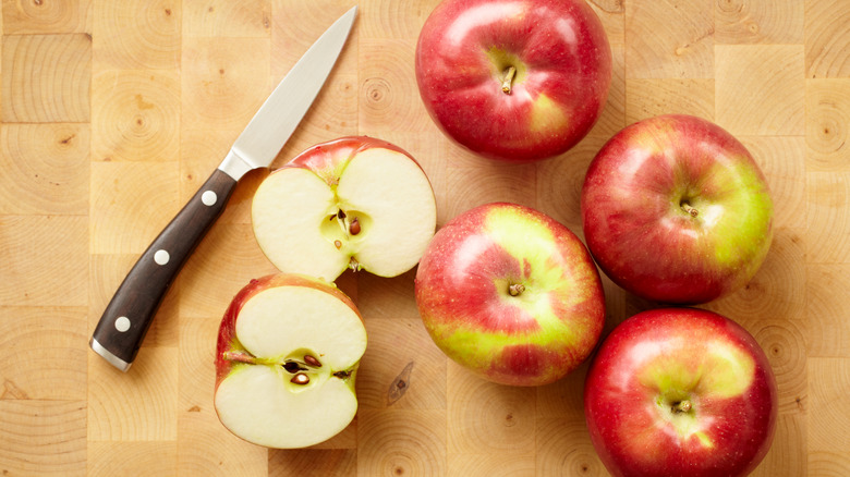 knife next to sliced and whole apples