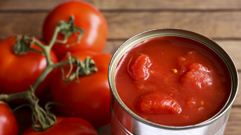 canned tomatoes next to several fresh ones