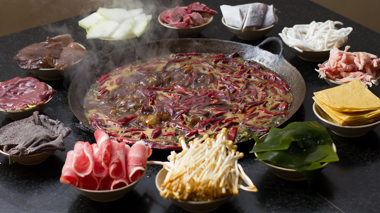 Hot pot surrounded by raw ingredients