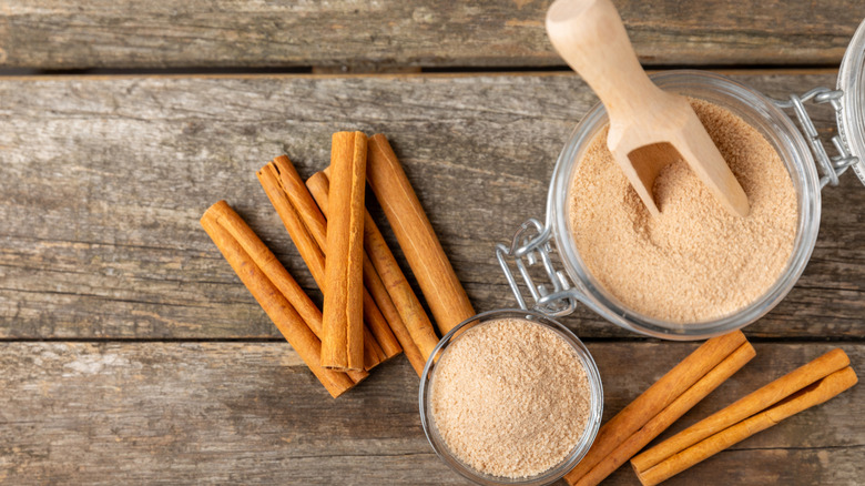 Cinnamon sticks and cinnamon sugar on a wooden table.