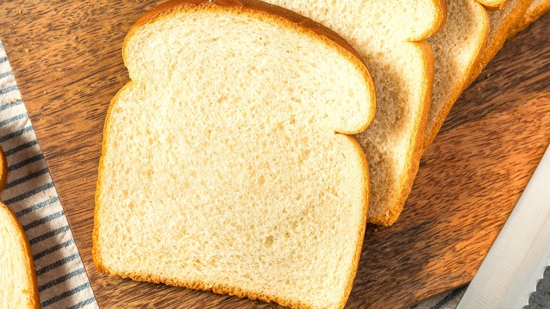 Sliced white bread on wood board