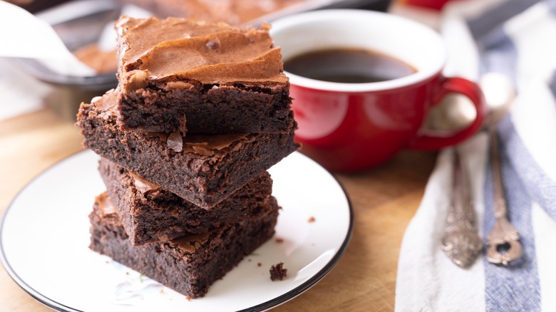 Stacked brownies on plate with cup of coffee