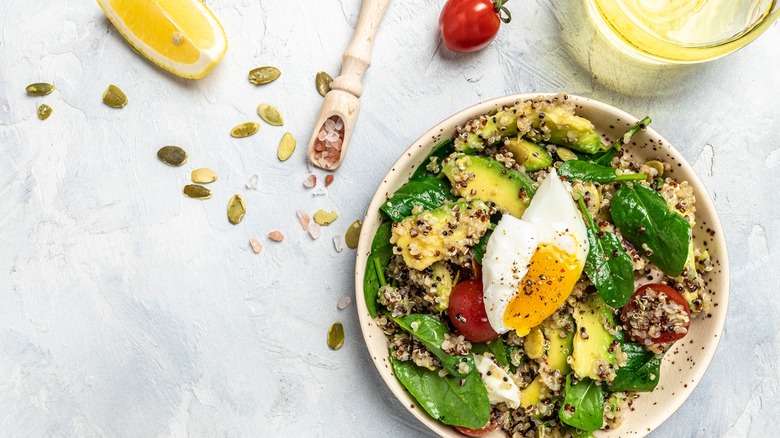 quinoa bowl with spinach, tomatoes, avocado, and an egg