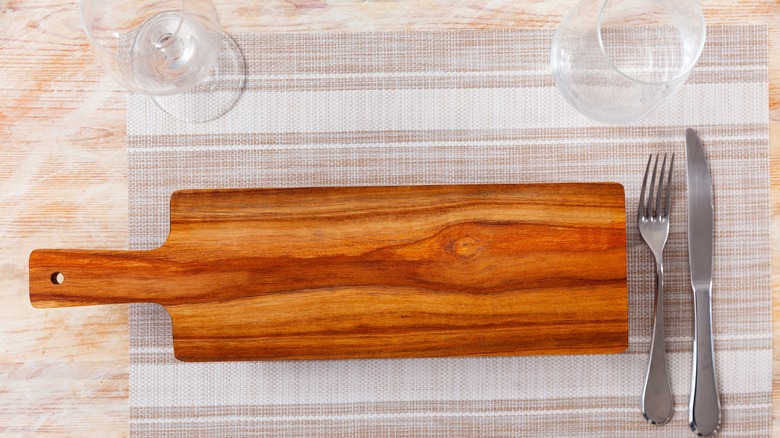 long wooden charcuterie board next to silverware