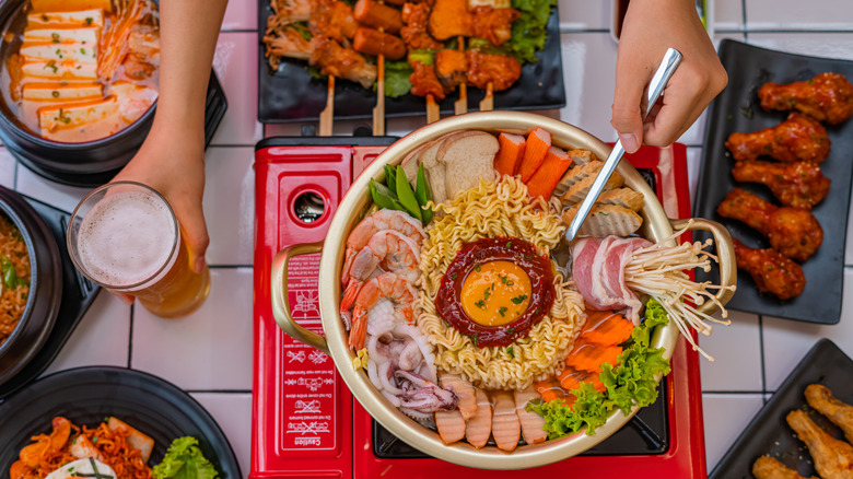 Budae jjigae with side dishes and a glass of beer