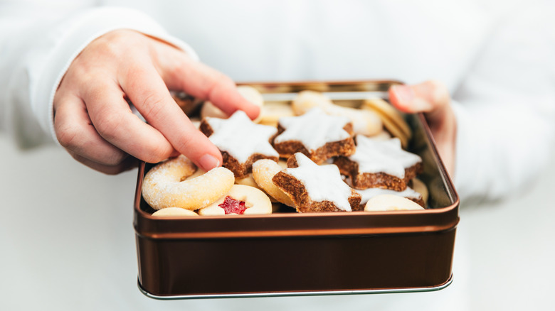 A person holds a Chanukah cookie tin filled with different types of cookies