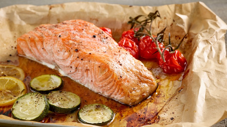 Roasted salmon with zucchini, tomatoes, and lemon on parchment paper
