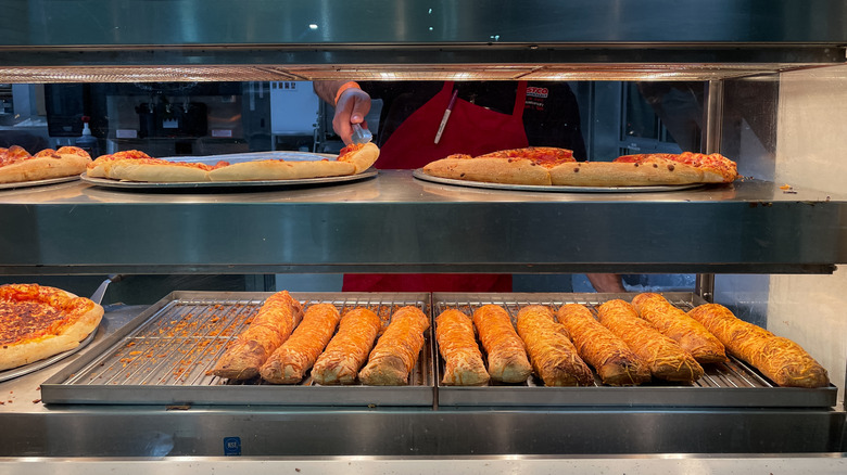 Chicken bakes and slices of pizza sit in a warming window of a Costco food court