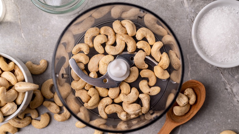Cashew nuts in a food processor with bowl of salt