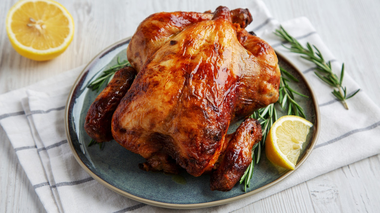 Roast chicken on a plate with lemons and thyme.