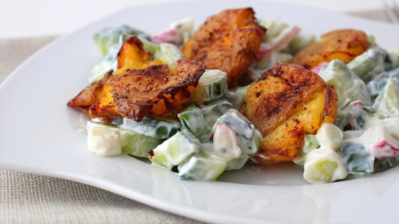 Creamy chopped vegetable salad topped with roasted smashed potatoes