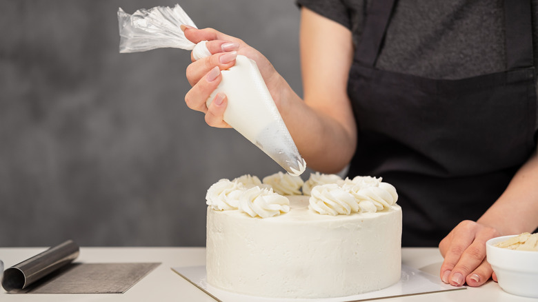 Piping white frosting onto cake