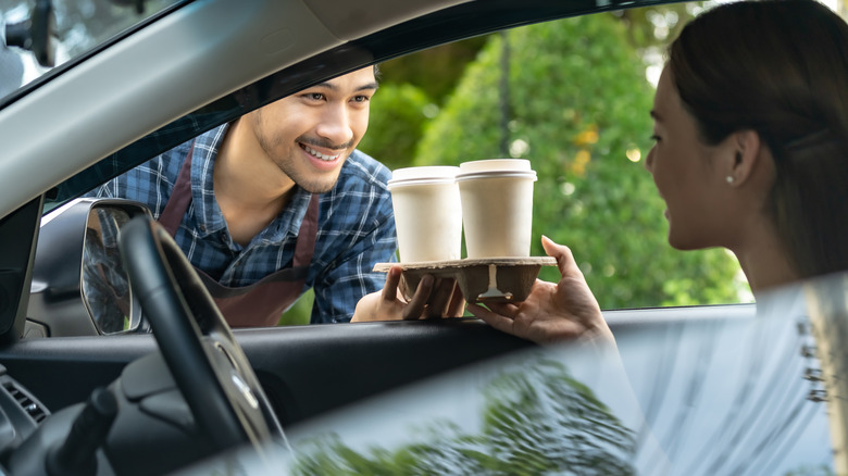 handing coffees to someone in a drive thru