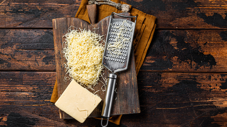 grated cheese and grater on chopping block