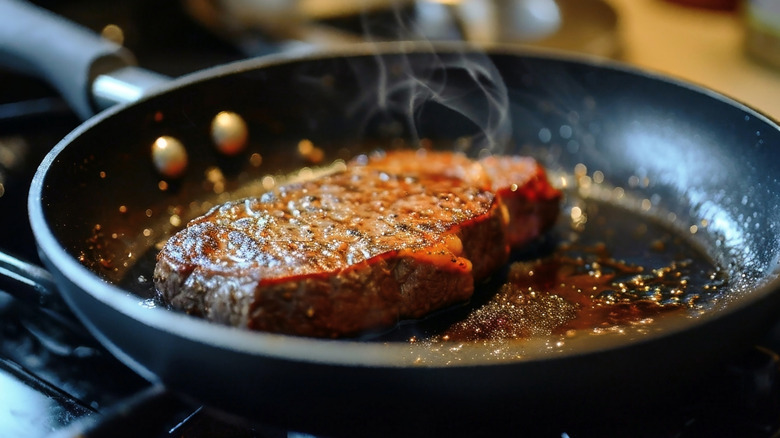 Steak searing in a pan.