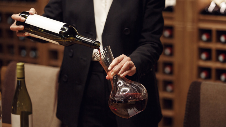 A sommelier decanting a bottle of red wine