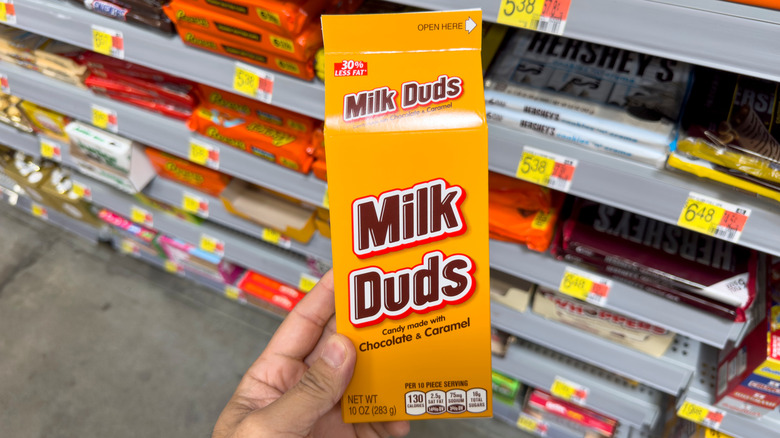 Hand holding a box of Milk Duds