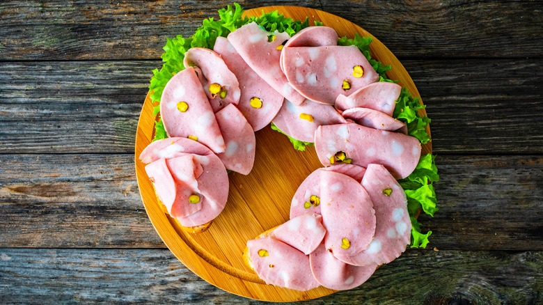Mortadella on cutting board with lettuce leaves