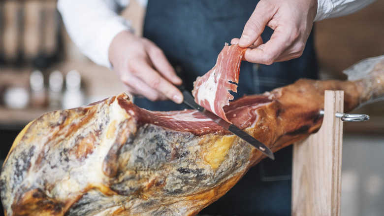Chef slicing ham from pork leg