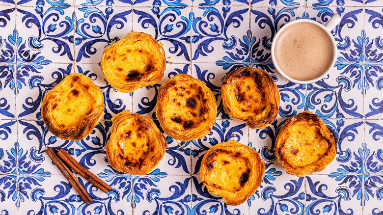 traditional Portuguese egg tart on tile background with cinnamon sticks