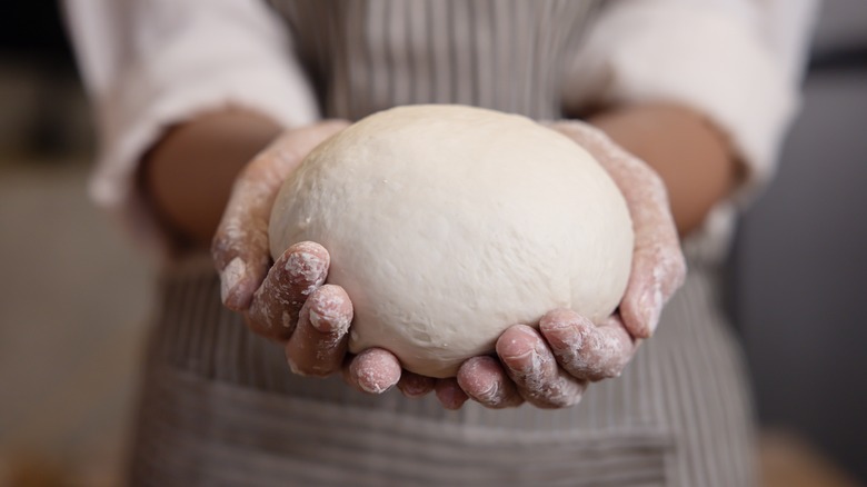 Floured hands holding bread dough